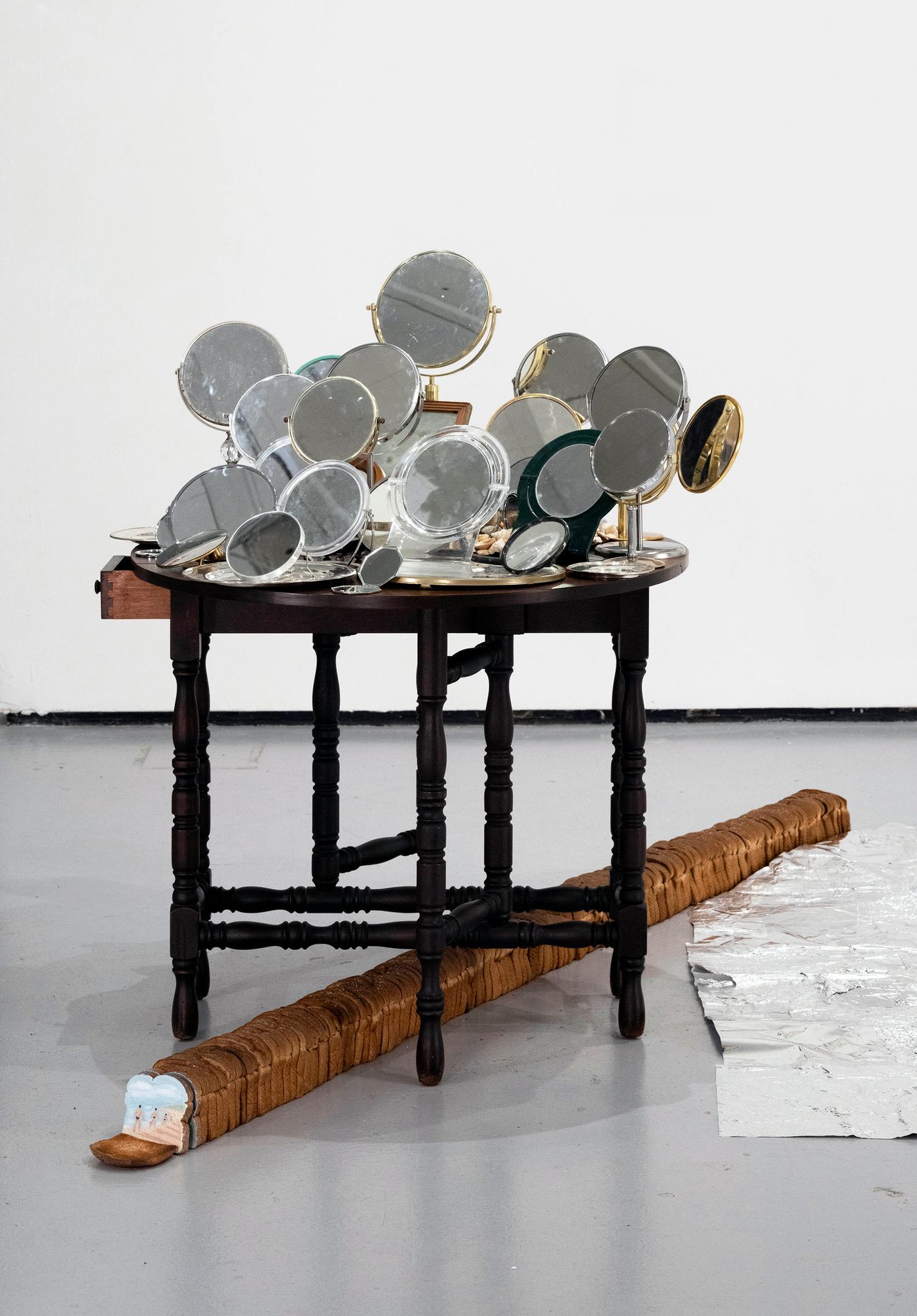Incarnations, 2022. Mirrors, silver plates, table, bread; 45 inches x 47 inches x 140 inches. Photo: Miraj Patel.